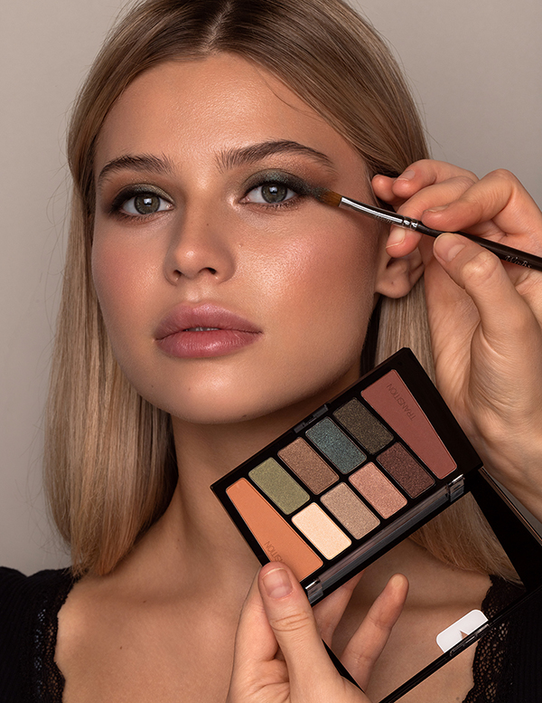 Pretty young woman holding cosmetics, smokey eyes makeup model